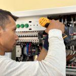 En elektriker arbetar med ett elskåp och installerar nya säkringar.